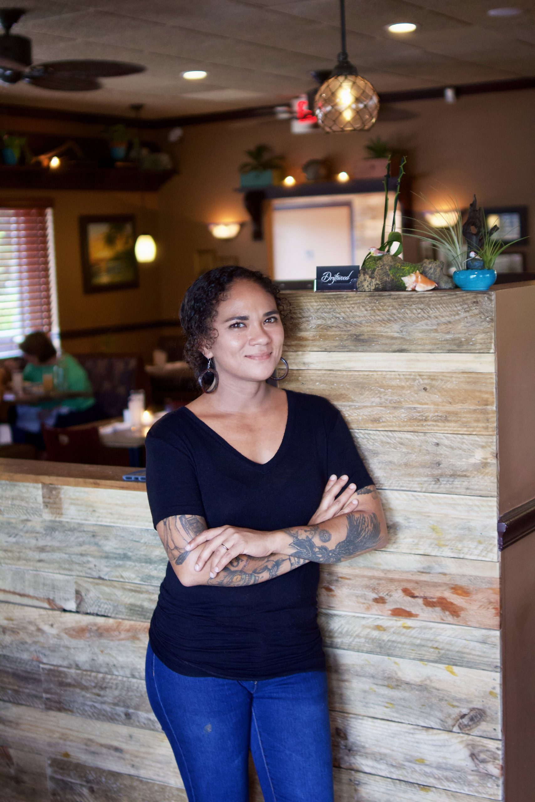 Photo portrait of Manager and Owner Ilia Gonzalez standing in front of the host stand inside of the restaurant