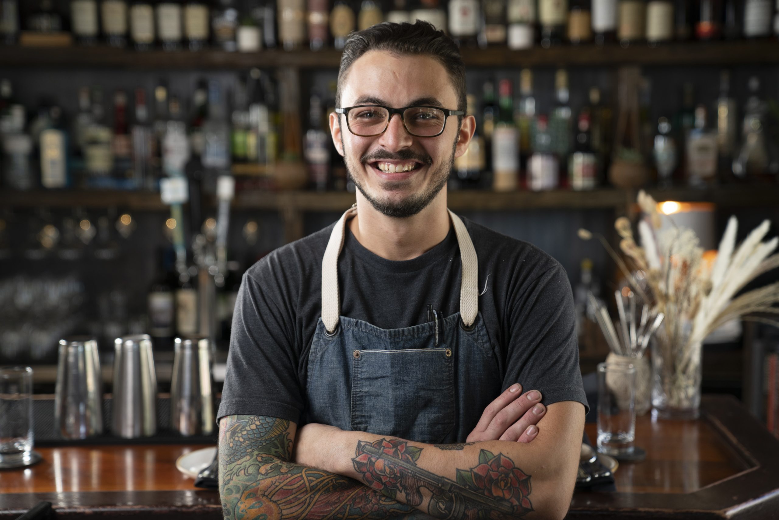 Photo portrait of Chef de Cuisine and partner Thomas Coombs Jr standing in front of the bar inside of the restaurant